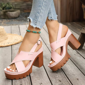 Pink open toe block heel sandals with cross straps and chunky sole.