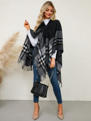 Asymmetric plaid fringe cape in black with fringe detail and V-neck.