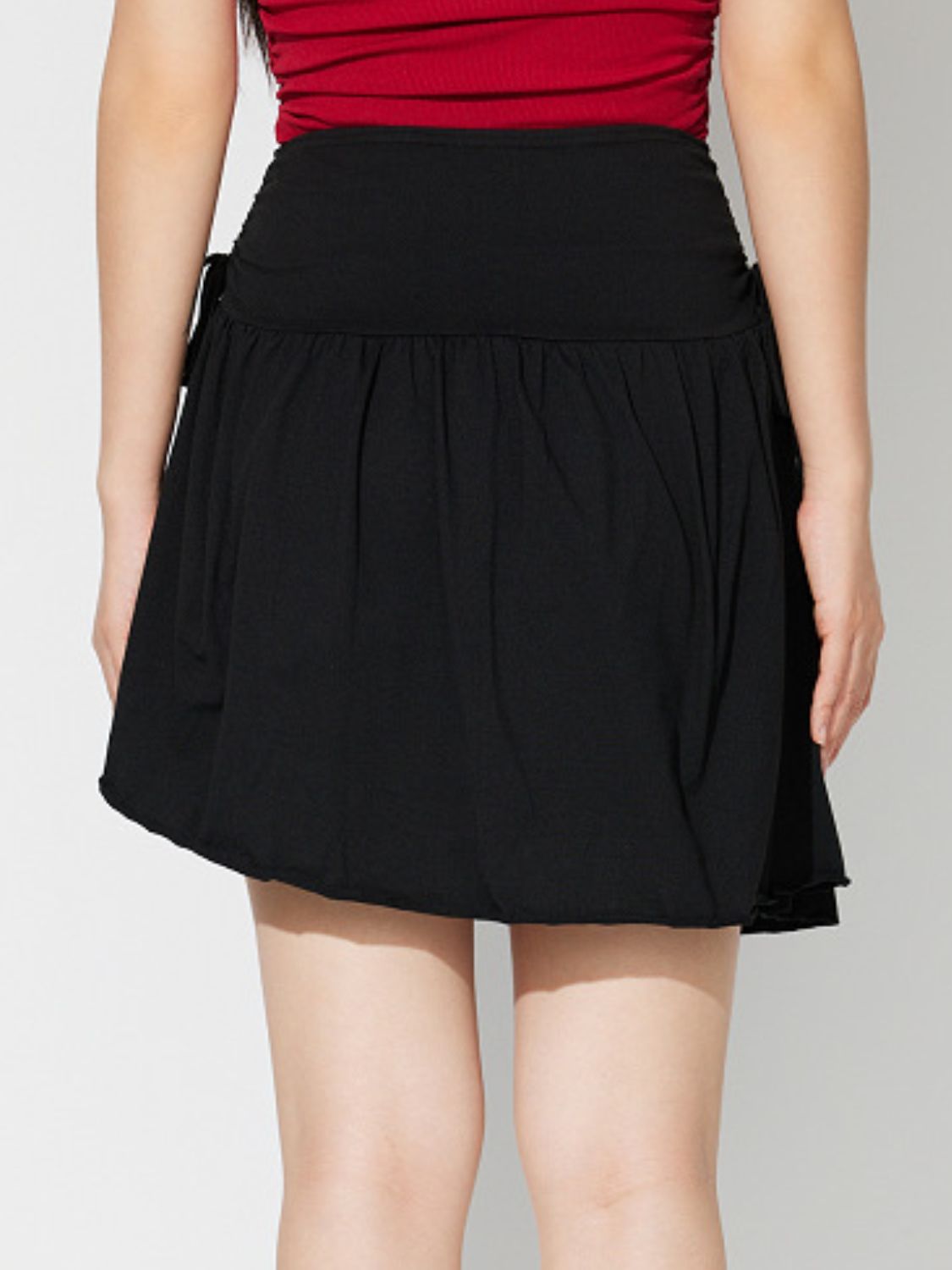 Black draped wrap mini skirt with tie detail and gathered waist