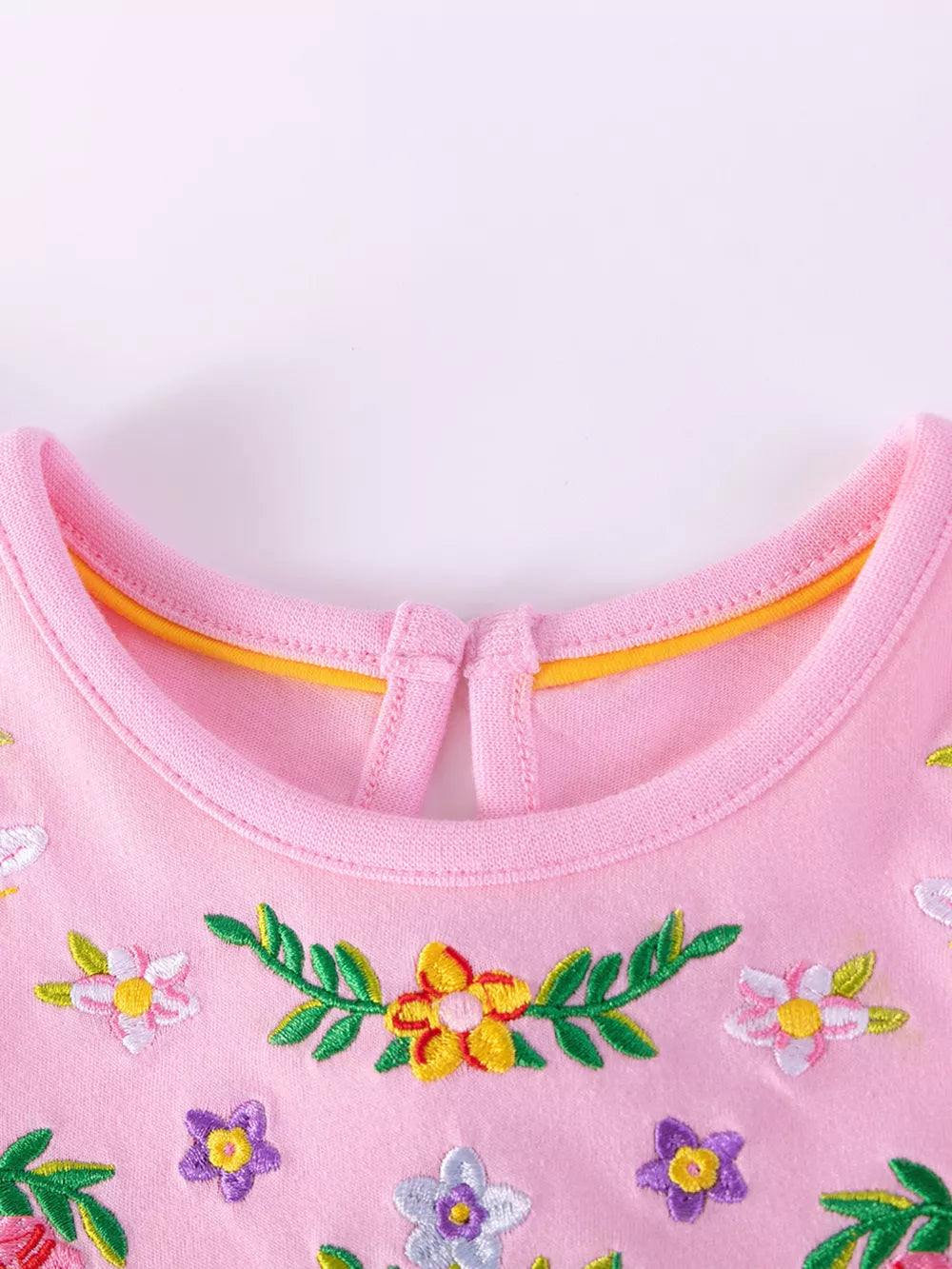 Pink cotton baby dress with embroidered floral pattern and ruffle sleeves.