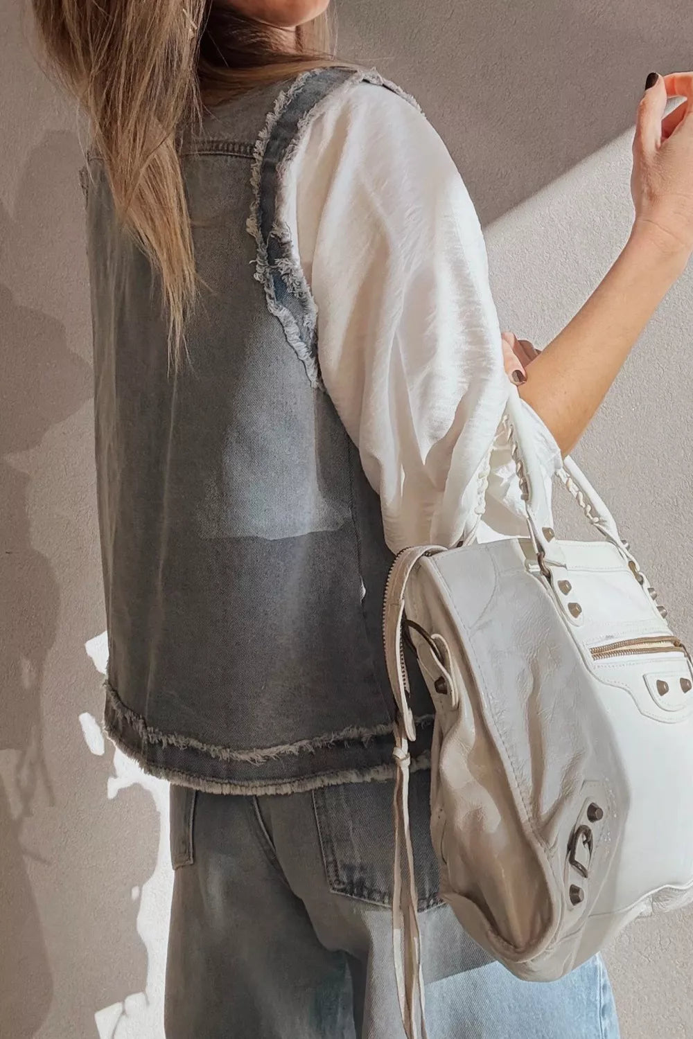 Denim vest with frayed edges and chest pockets, styled with a white top and jeans.