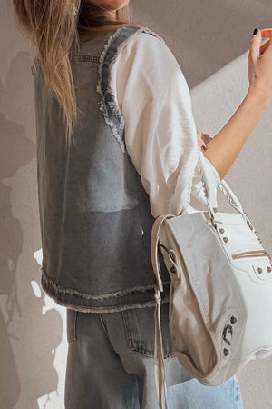 Denim vest with frayed edges and chest pockets, styled with a white top and jeans.