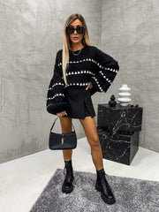 Black knit sweater with white textured stripes and balloon sleeves.