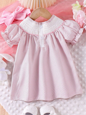 Baby dress with pink polka dots, smocked white collar, and puff sleeves.