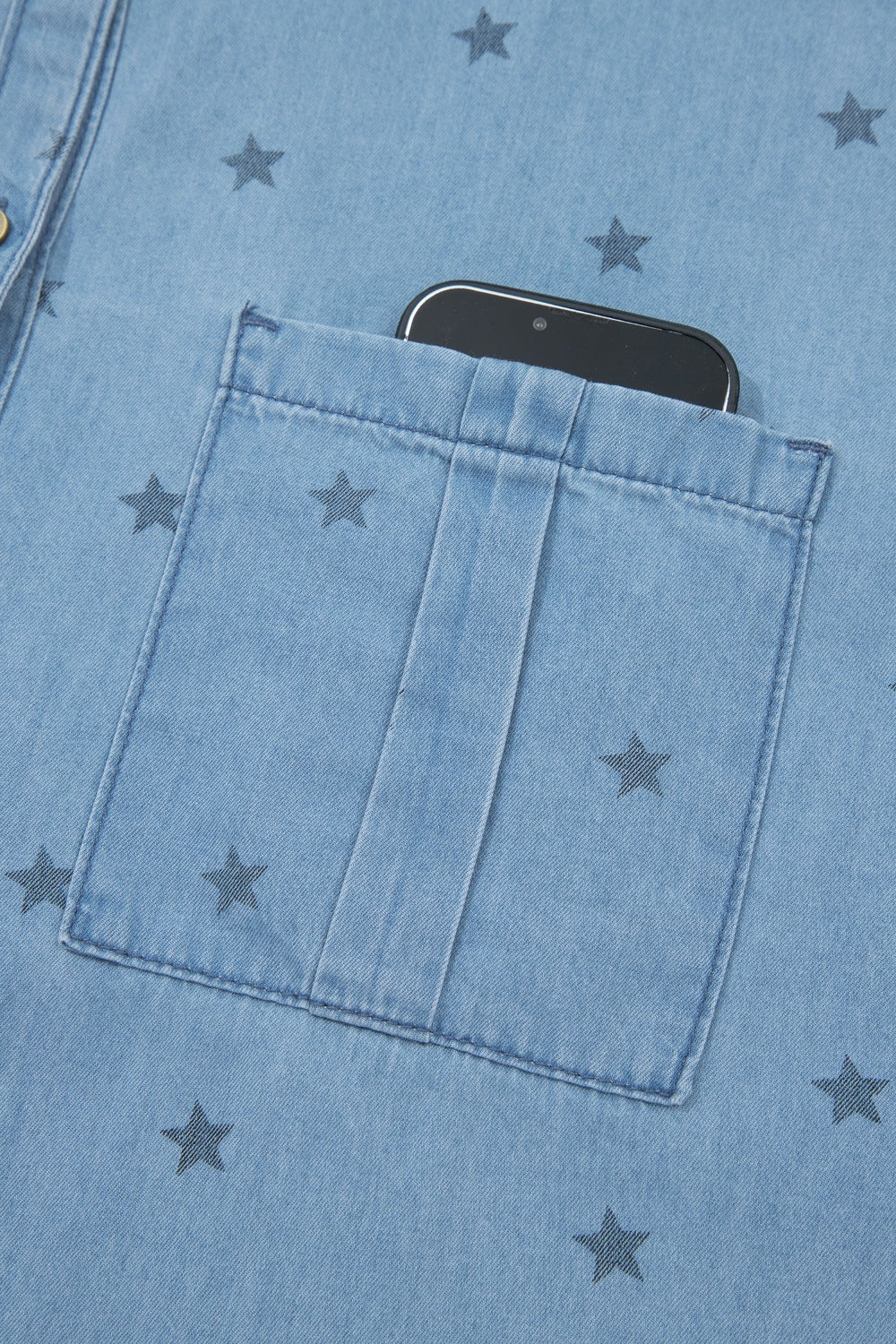 Light blue denim shirt with dark star print and a phone in the chest pocket.
