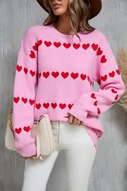 Pink knit pullover sweater with red heart stripe pattern, crew neck, and long sleeves.