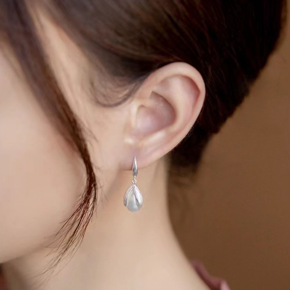 Lustrous pearl drop earrings in silver with a delicate petal design.