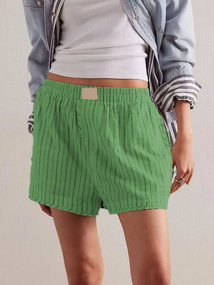 Green pinstripe boxer shorts with elastic waistband and beige patch detail.