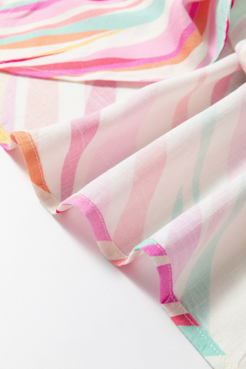 Prismatic stripe henley blouse in blush pink with a soft, flowing fabric.