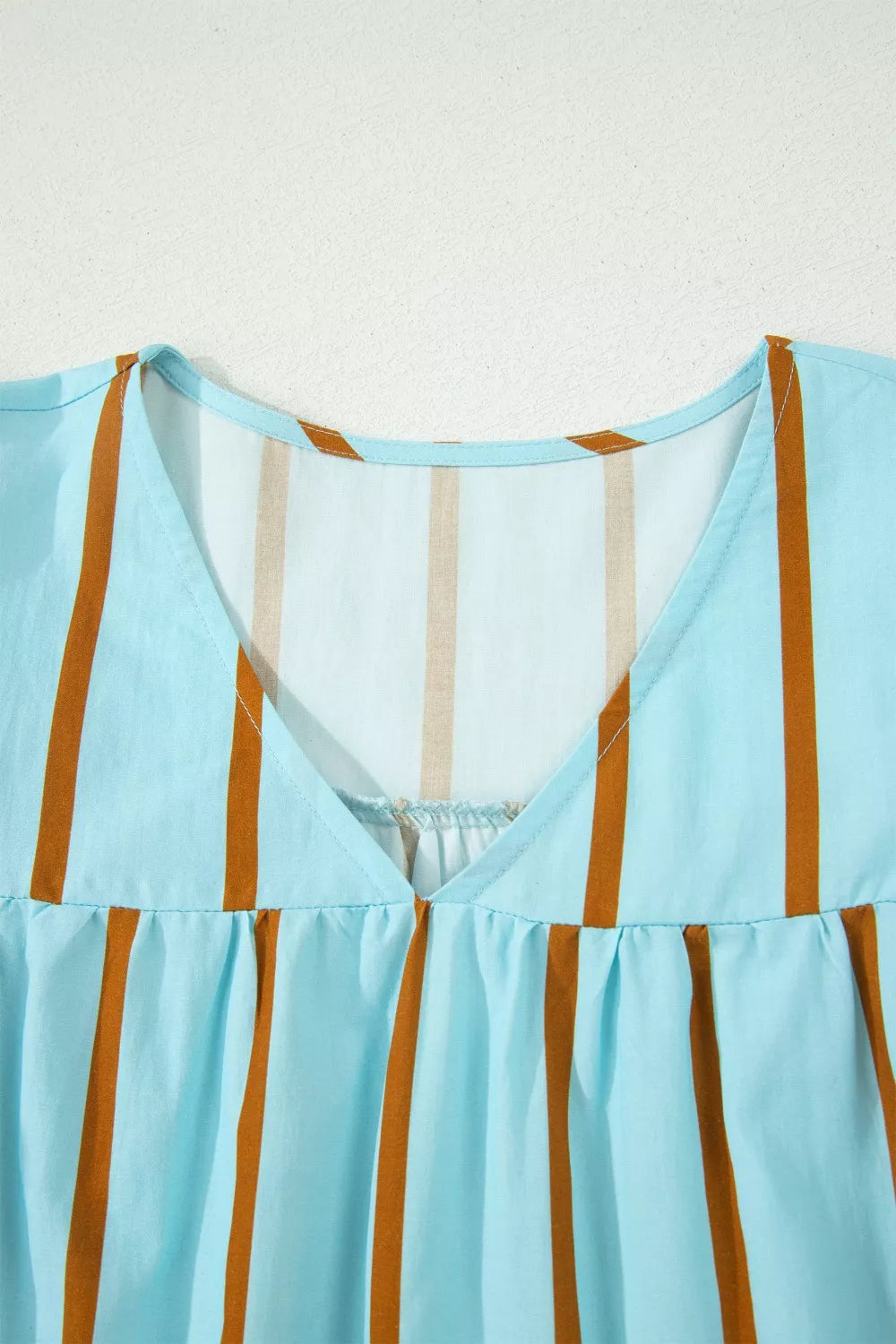 Light blue cotton blend blouse with brown vertical stripes and a V-neckline.