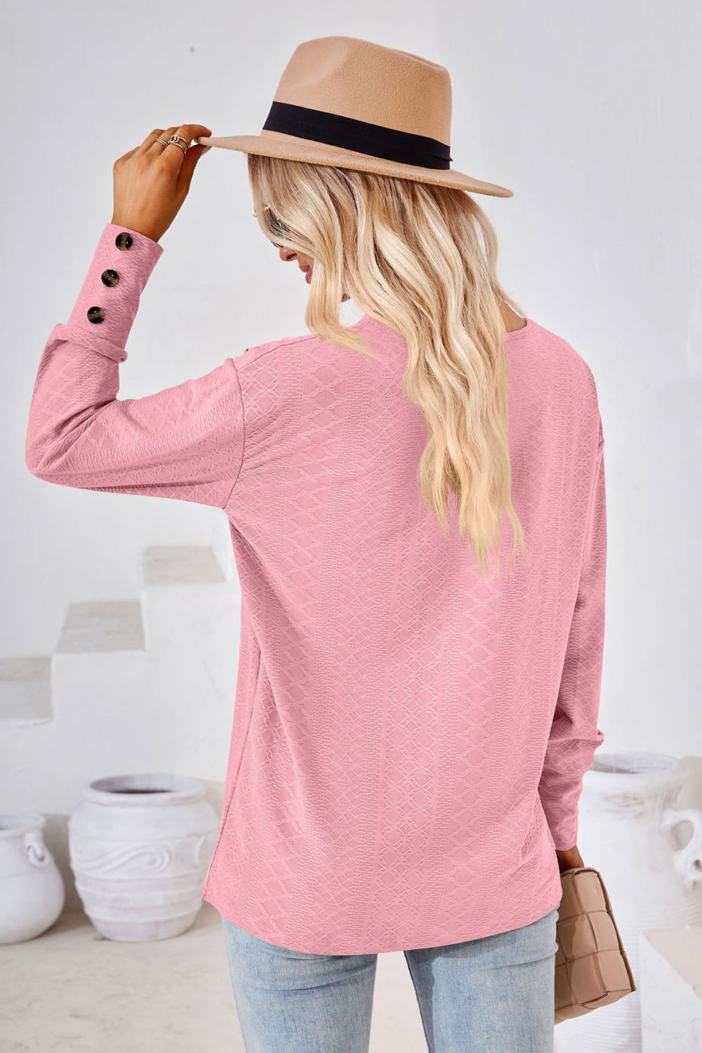 Blush pink textured blouse with button cuff detail and V-neck.