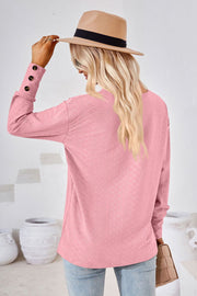 Blush pink textured blouse with button cuff detail and V-neck.