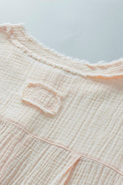 Beige textured gauze henley blouse with raw edge neckline and chest detail.