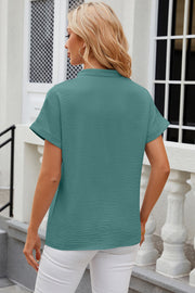 Textured turquoise blouse with rolled sleeves and V-neck detail.