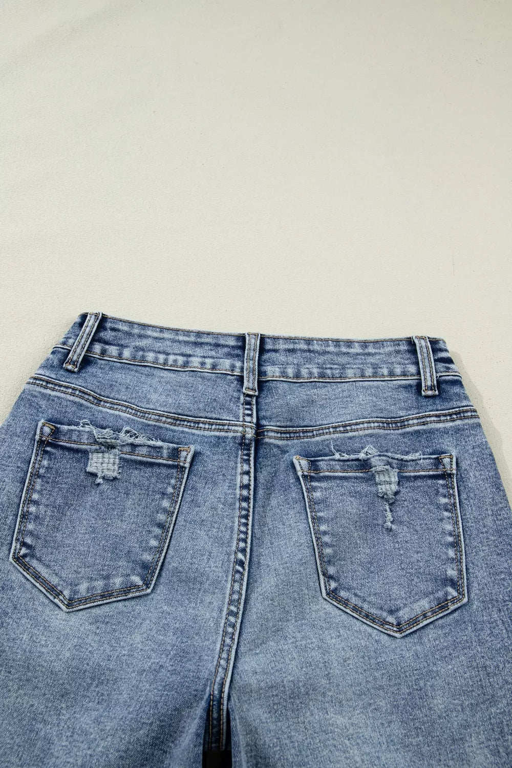 Cuffed mid-rise relaxed fit jeans in light wash denim with distressed back pockets.
