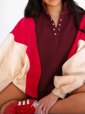 Oversized cotton color block sweatshirt with button neckline in maroon, red, and cream.