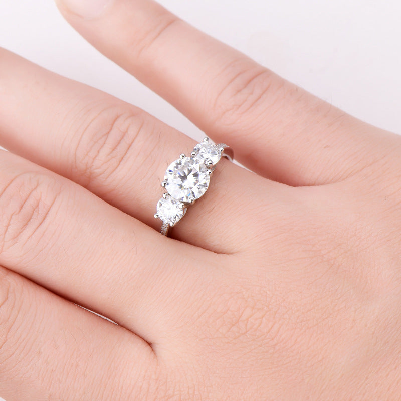 Silver ring with three round moissanite stones and a delicate band.