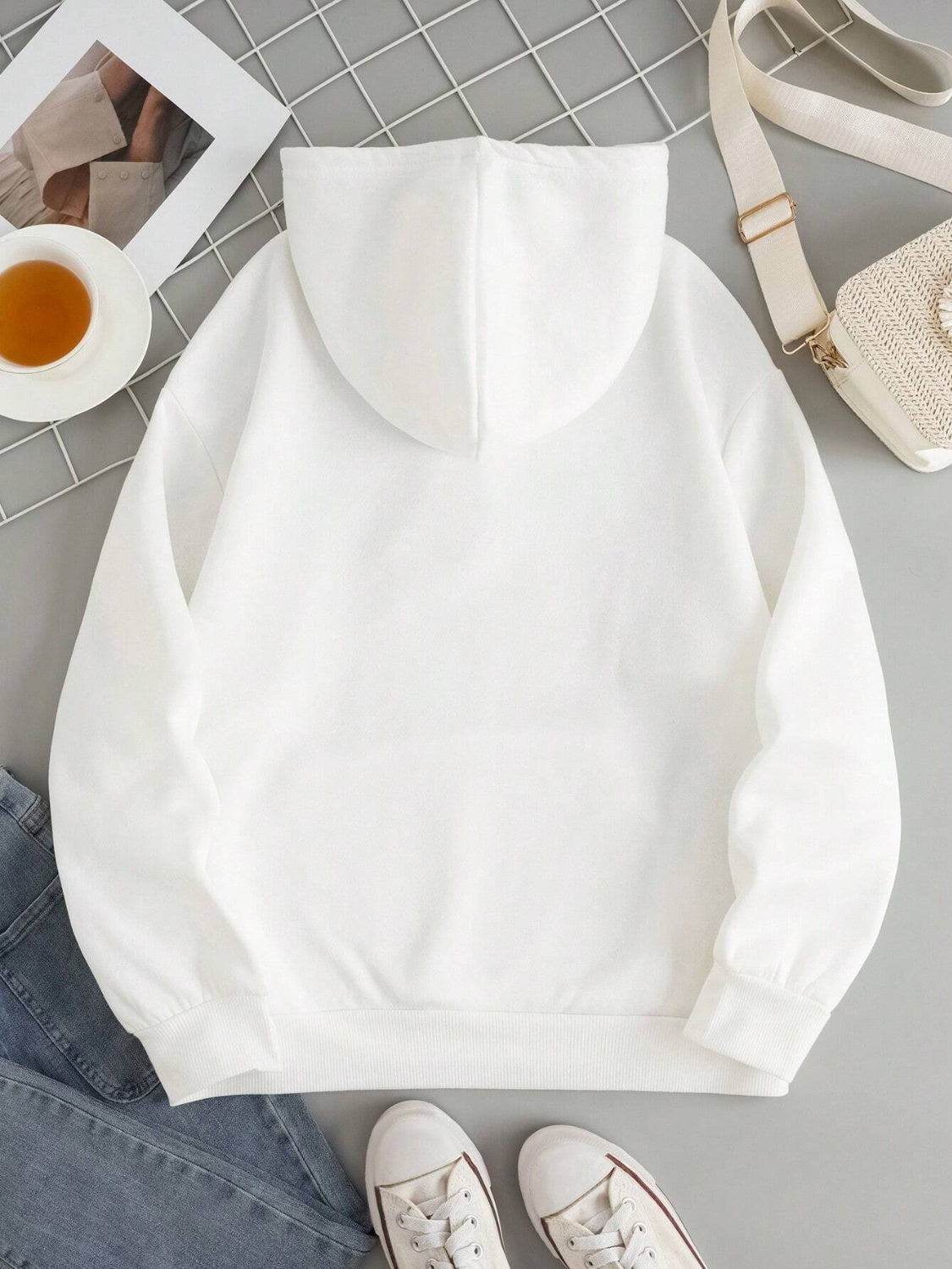 White oversized hoodie with pouch pocket and cuffed sleeves, styled casually.