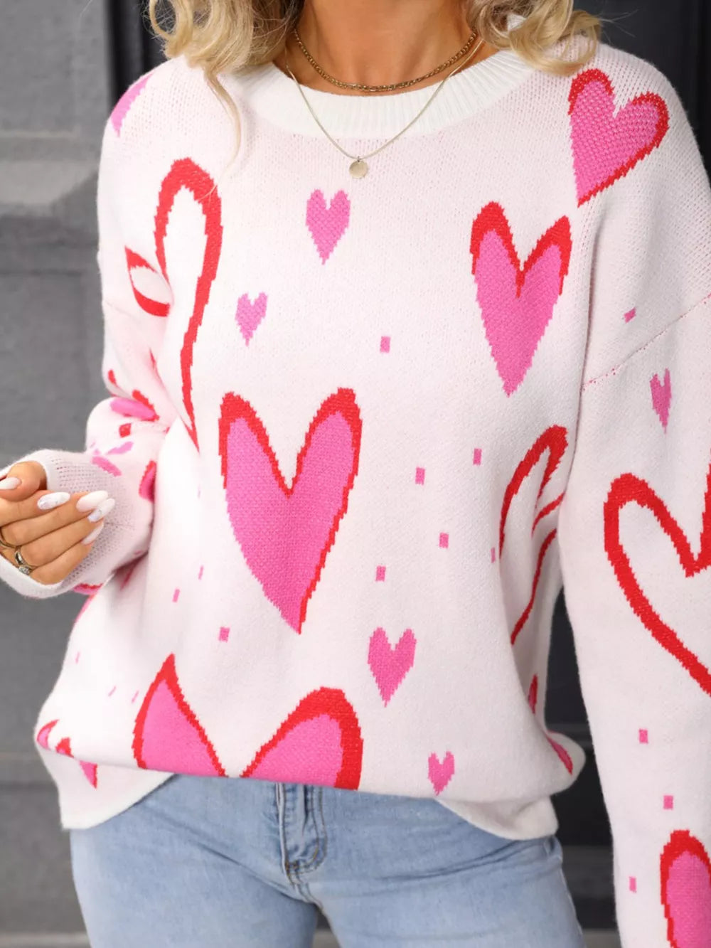 White acrylic crew neck sweater with a pink and red heart pattern