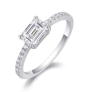 Elegant moissanite ring with emerald-cut center stone and pavé band in sterling silver.