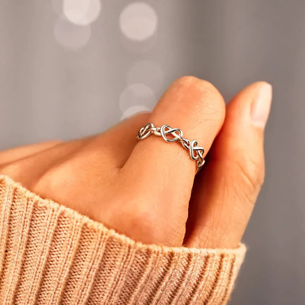 Sterling silver ring with intertwined heart motif, delicate and classic design.