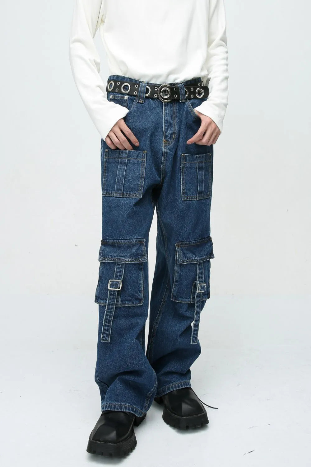 Medium wash denim cargo pants with buckle pockets and straps.