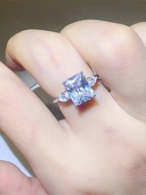 Silver ring with emerald cut center stone and pear accent stones.