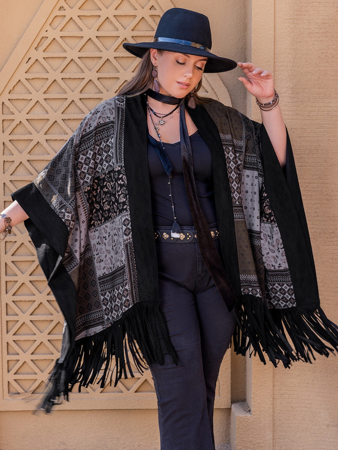 Black patchwork print kimono with fringe and wide sleeves, worn open over a black tank top.