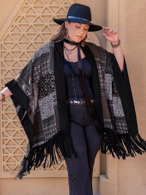 Black patchwork print kimono with fringe and wide sleeves, worn open over a black tank top.