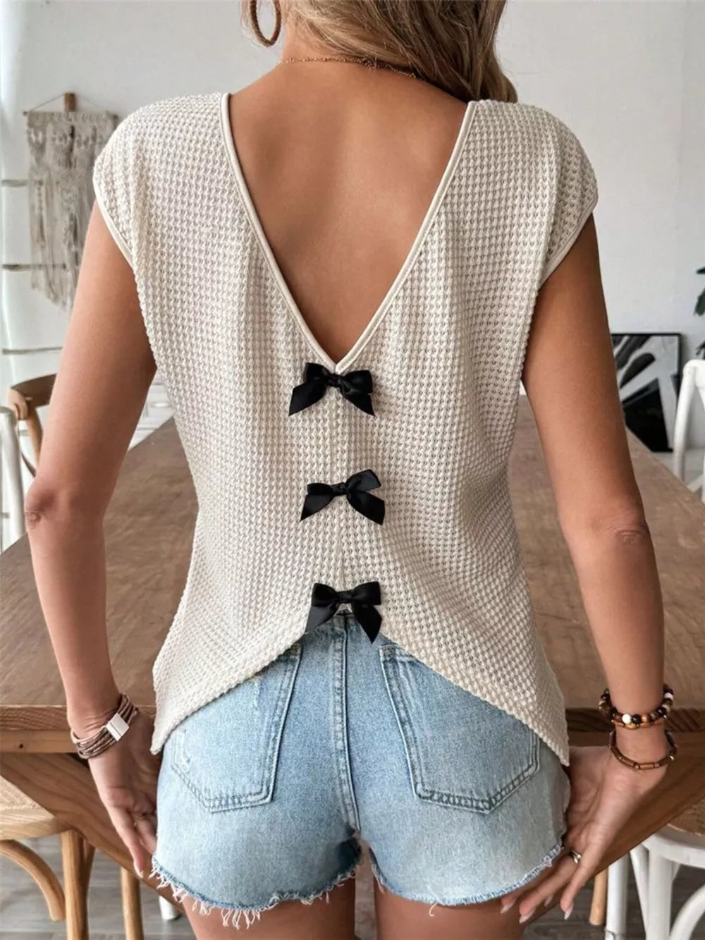 Apricot waffle knit v-neck shirt with cap sleeves and three black bow details down the back.