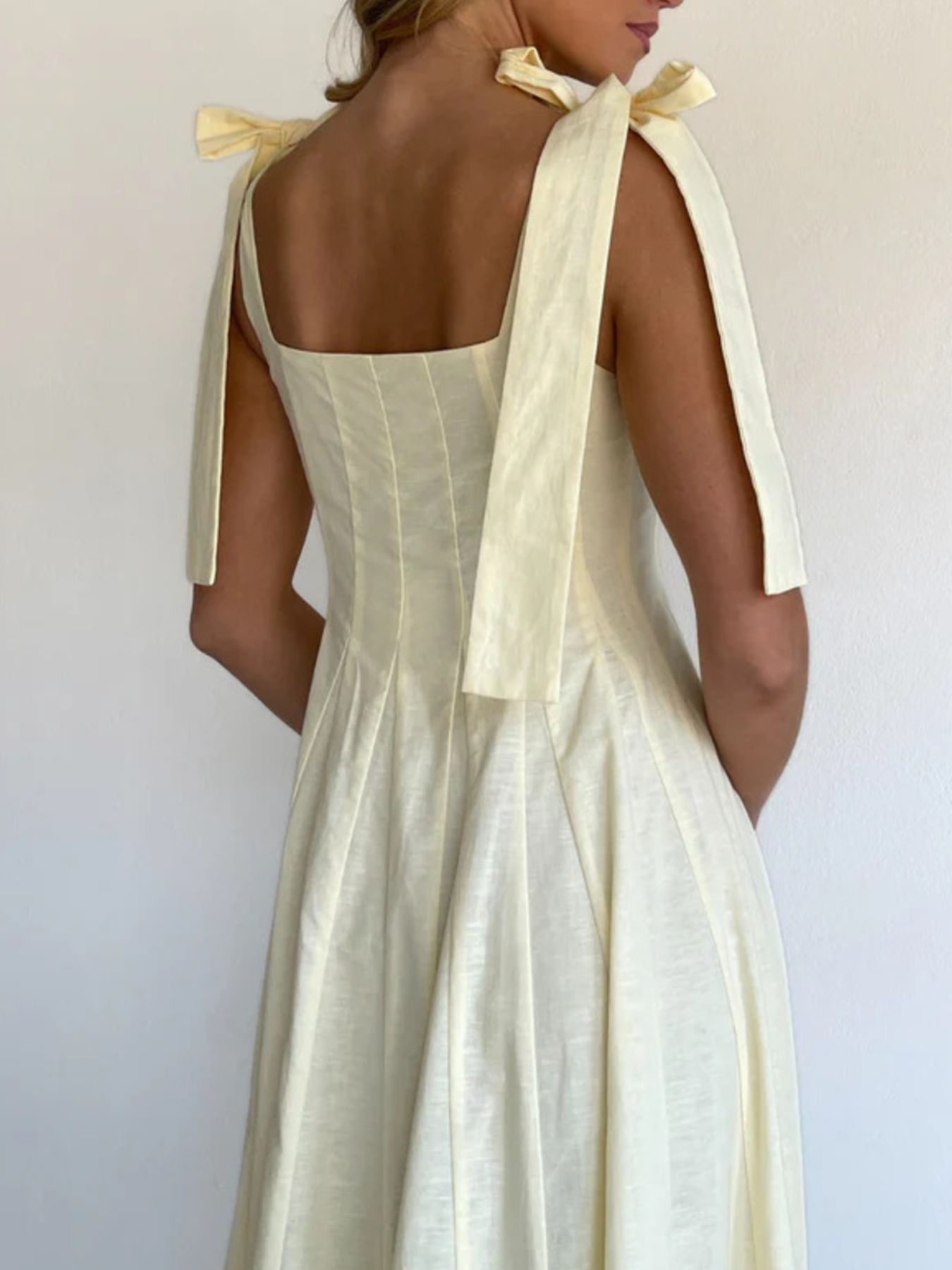 Yellow maxi dress with bow tie shoulder straps and square neckline.