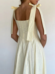 Yellow maxi dress with bow tie shoulder straps and square neckline.