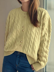 Pastel yellow cable knit cardigan with puff sleeves and gold buttons.