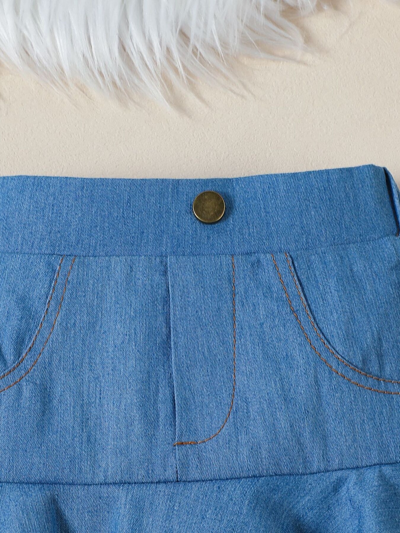 Toddler denim skirt with button closure and contrast stitching on pockets.