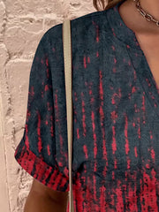 Bohemian tapestry henley blouse with a dark green and red tie-dye pattern.