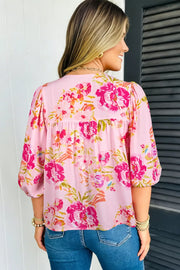 Pink floral tie-neck blouse with gathered yoke and puff sleeves.