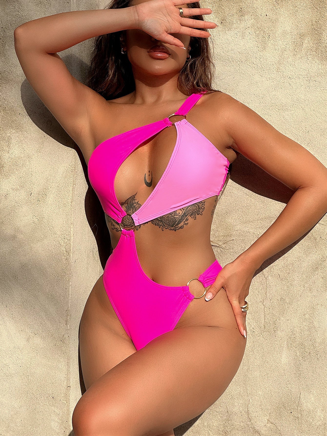 Hot pink one-piece swimsuit with asymmetric ring detail and cut-out sides