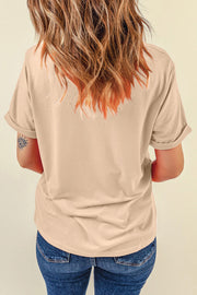 Tan graphic t-shirt with rolled sleeves and a subtle eye tattoo on the arm.