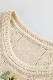 Beige cable knit vest with floral embroidery and open knit details.