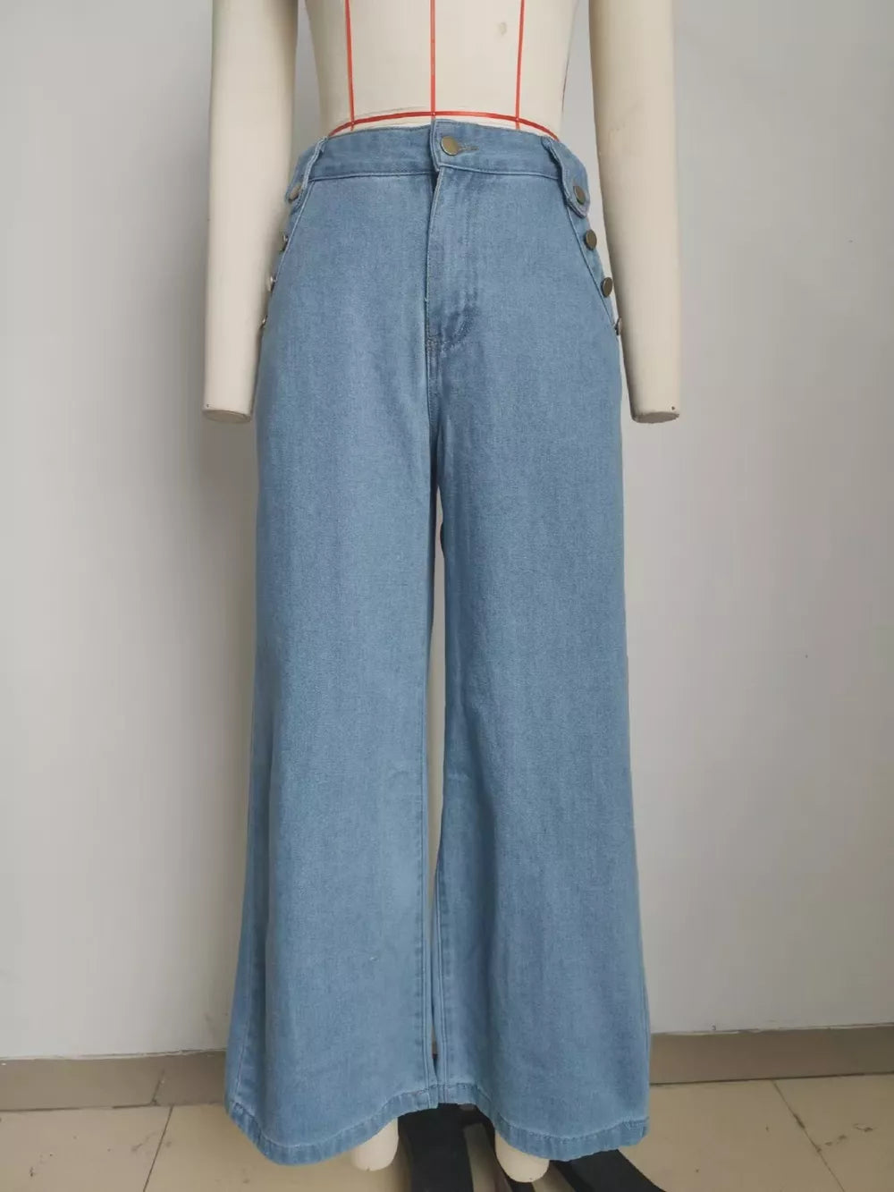 Light wash denim wide-leg pants with button details on the sides and front.