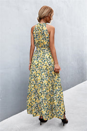 Yellow floral print maxi dress with halter neckline and tiered skirt.