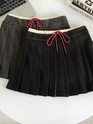 Chic pleated skirt in black and dark gray with drawstring waist and white trim.