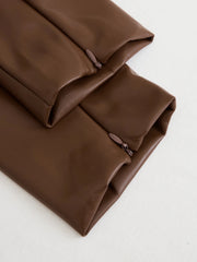 Brown leather midi dress detail showing zipper closure and fabric texture.