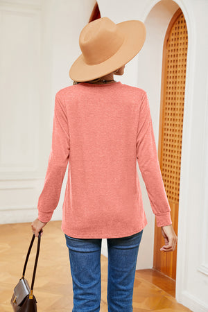 Coral long sleeve henley top with crew neck and cuffed sleeves, worn with jeans.