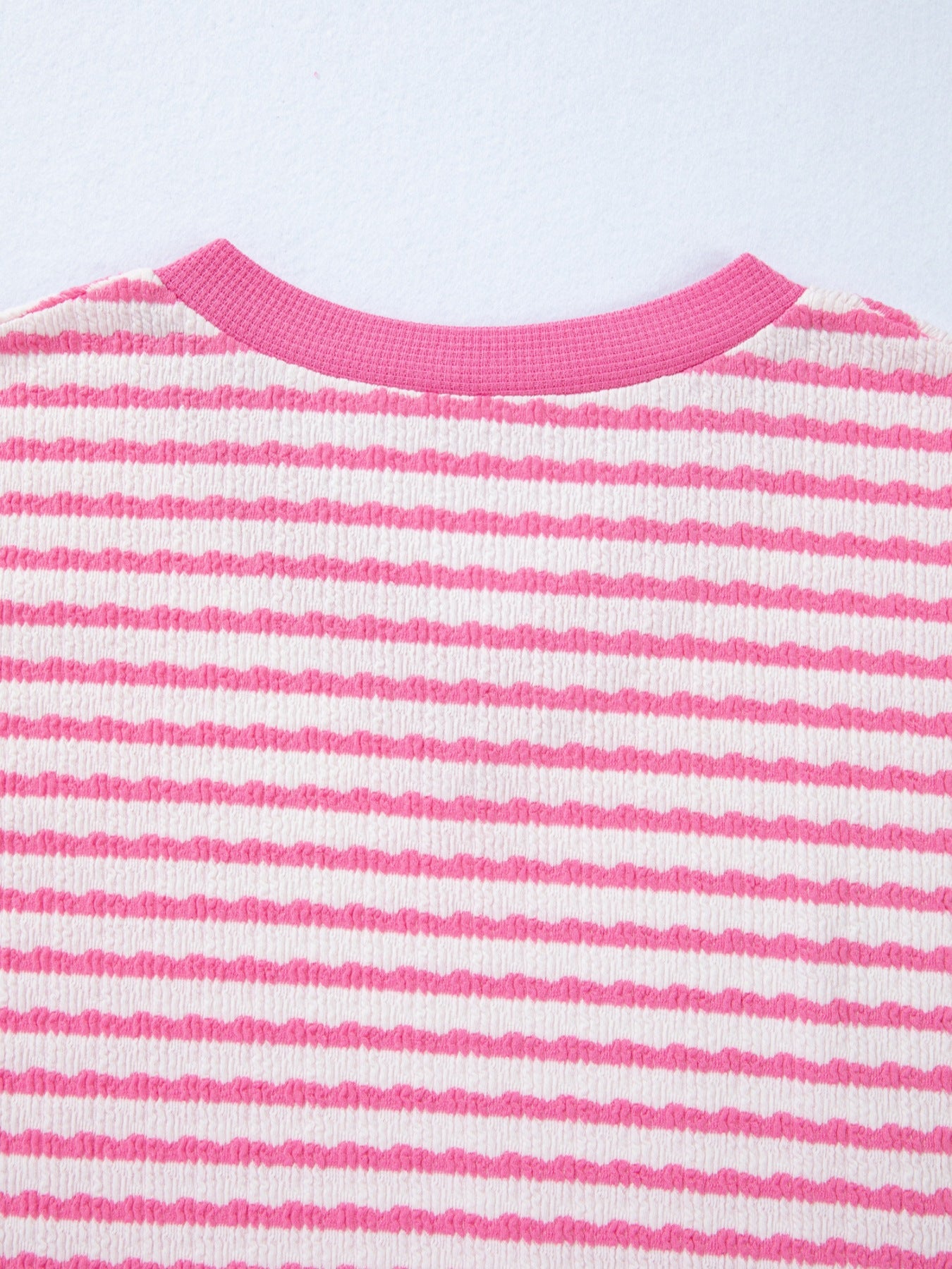 Textured pink and white striped t-shirt with a V-neck and ribbed collar.