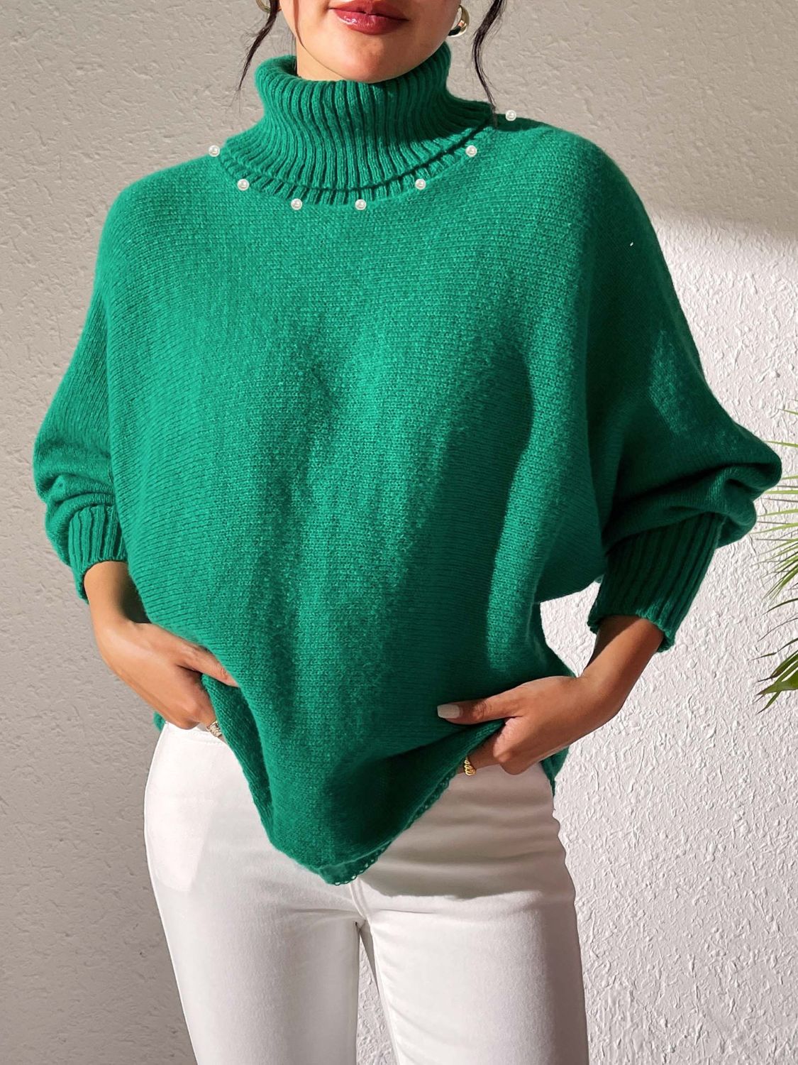 Green knit sweater with dolman sleeves, turtleneck, and pearl embellishments.