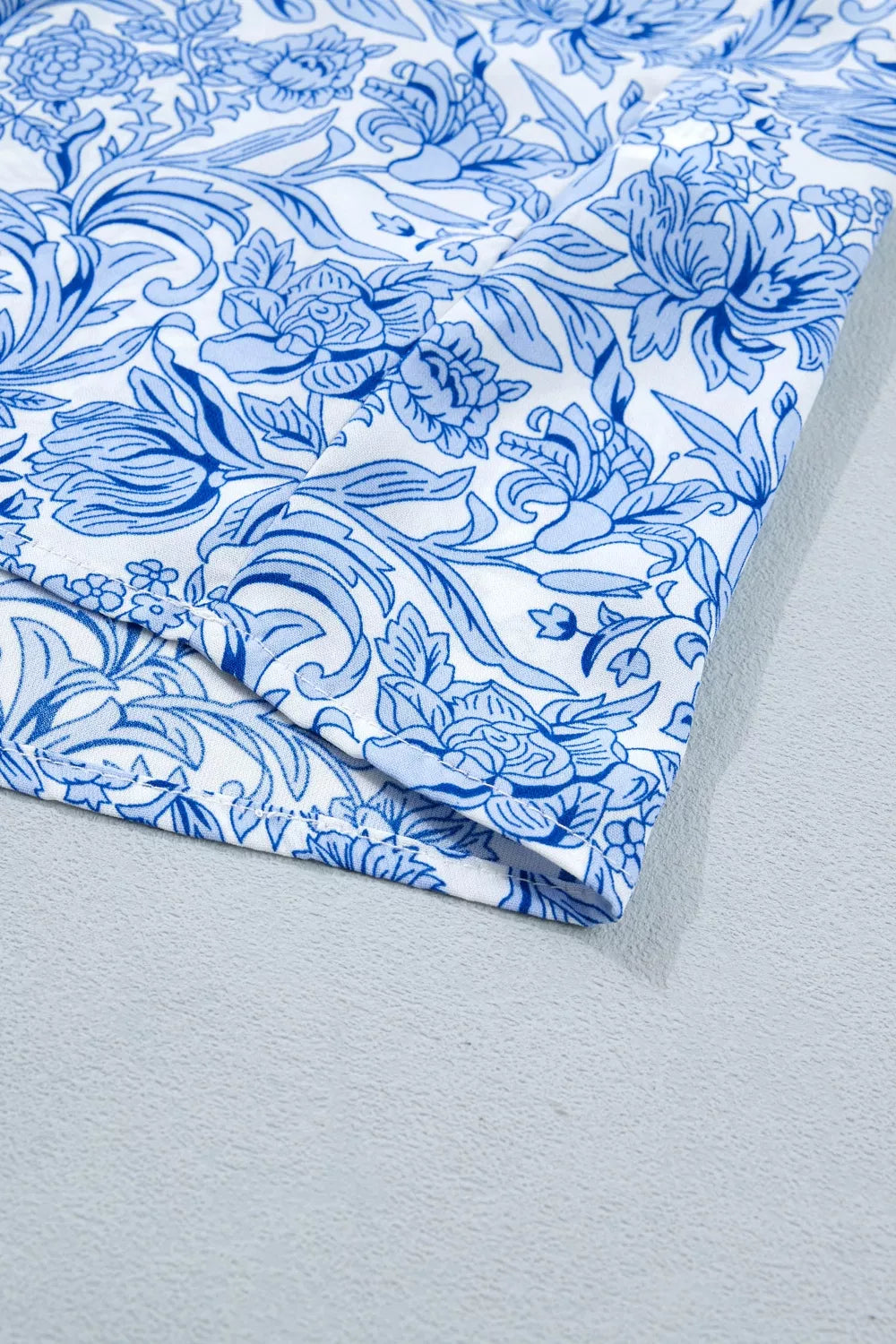 Floral pleated blouse with square neckline in blue and white polyester.