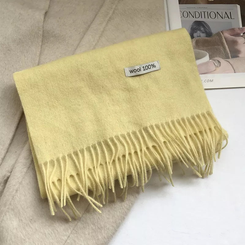 Luxurious wool knit scarf in cream yellow with fringes and a wool 100% tag.
