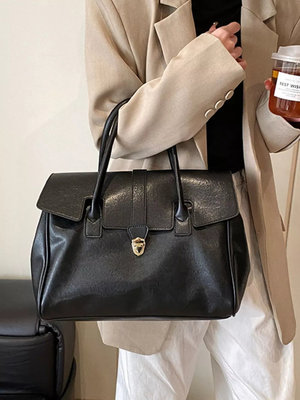 Black pu leather tote bag with buckle detail and gold hardware.