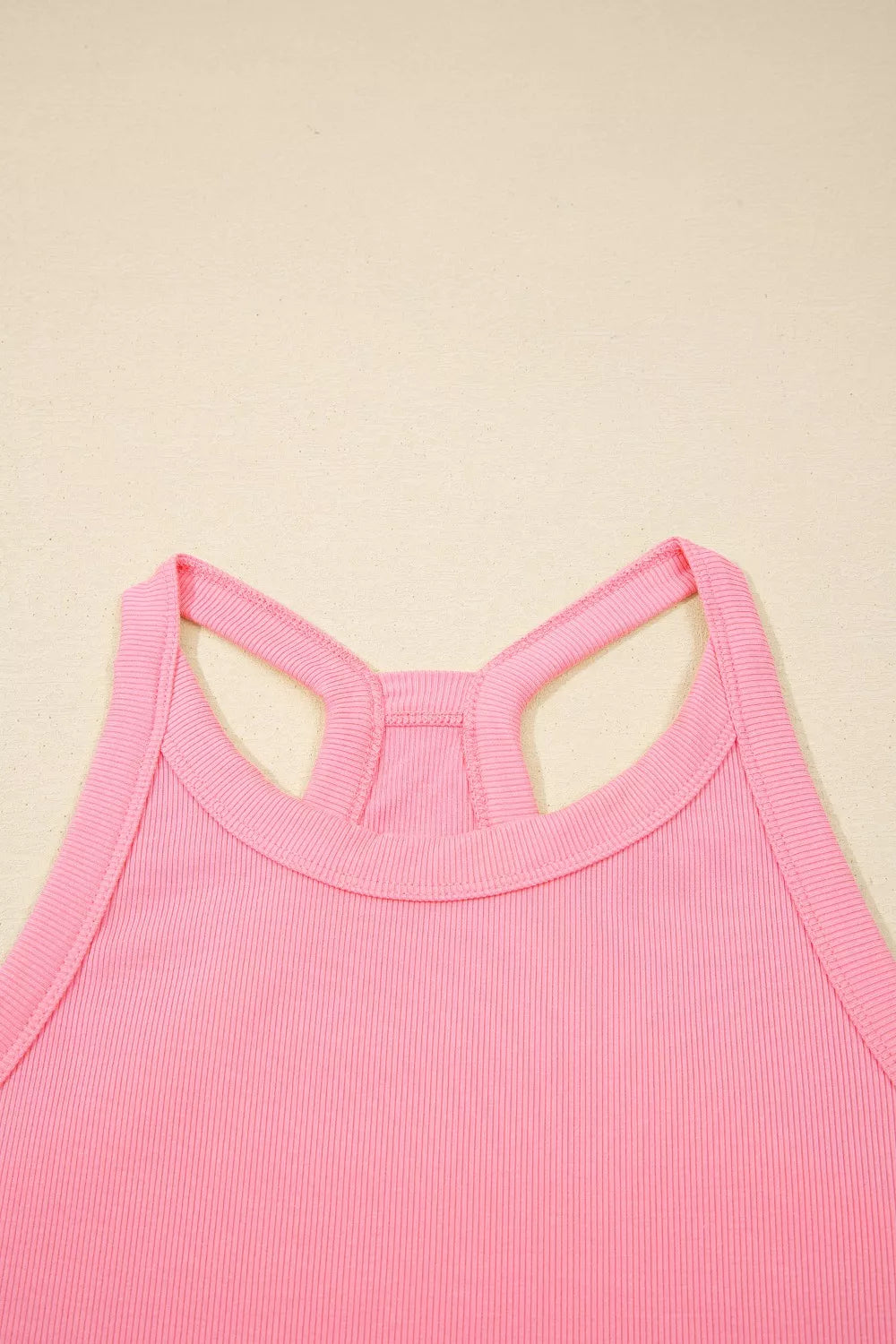 Dusty pink ribbed cropped tank top with racerback detail and contrast stitching.